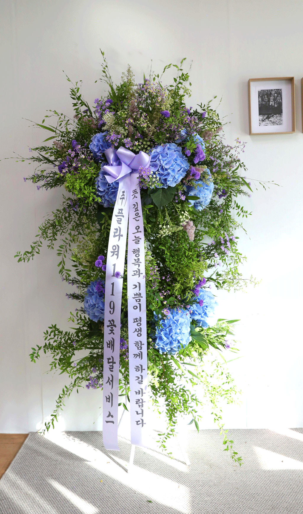 파란 수국과 그린 수국의 고운 조화가 돋보이는
이 결혼식 축하 화환은 자연의 싱그러움을 담아낸 작품입니다.