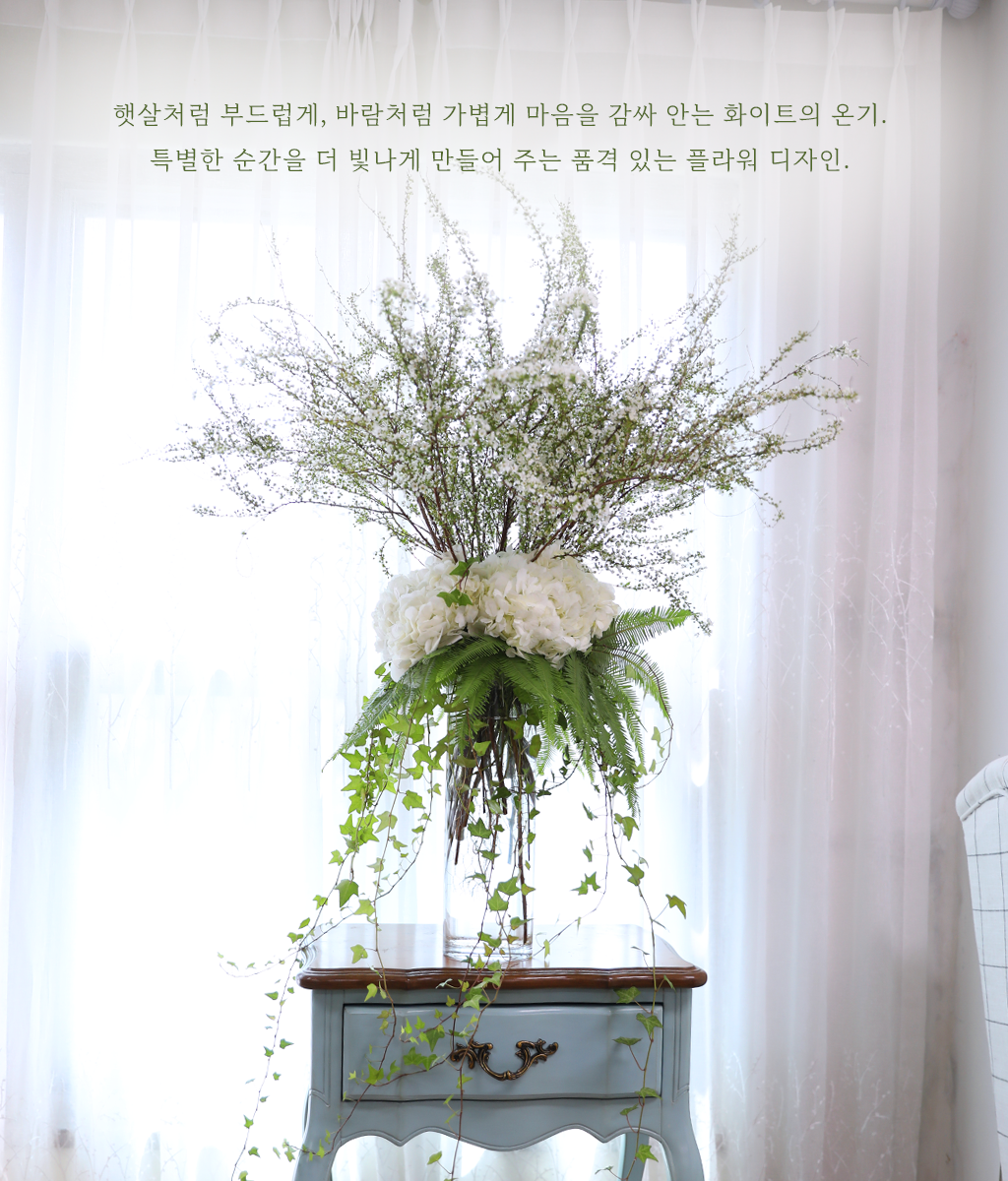 층층이 쌓인 화이트 톤의 텍스처가 깨끗하고 풍성한 볼륨감을 보여줍니다.
아래로 흐르는 아이비 덩굴의 라인감이 더해져 자연스러운 율동감과 사랑스러움이 공존합니다.
특별한 기념일, 평범한 일상을 영화 속 한 장면처럼 아름답게 기록하고 싶은 순간에 함께하기 좋습니다.