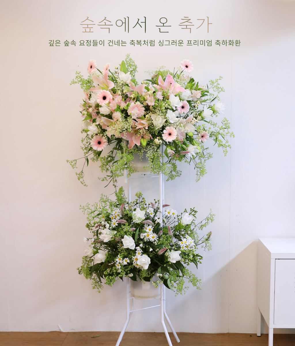 <br>숲속에서 온 축가</br>
연핑크와 화이트 톤의 꽃을 중심으로 풍성하게 어레인지해, 부드럽고 화사한 축하의 분위기를 전하는 플라워 화환입니다.
상단과 하단을 나누어 구성한 디자인으로 공간에 자연스러운 볼륨감과 안정감을 더해줍니다.